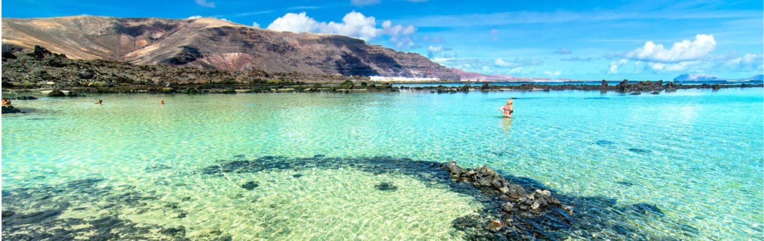 Caleta Blanco Lanzarote, laguna natural de aguas turquesas cristalinas con formaciones volcánicas y bañistas