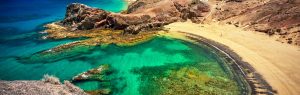 Playa de Papagayo en Lanzarote con aguas turquesas cristalinas, arena dorada y rocas volcánicas rojizas