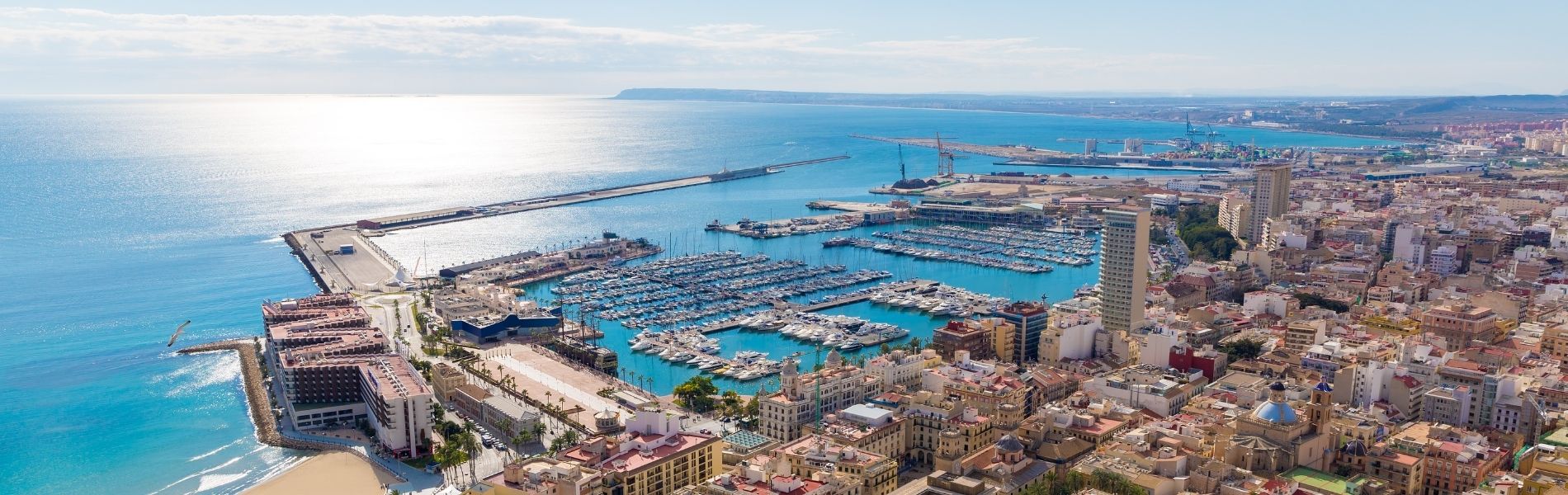 Vista aérea del puerto deportivo de Alicante con marina llena de veleros, ciudad mediterránea y mar azul turquesa