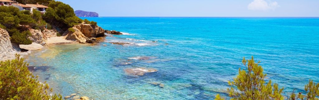Cala transparente de Benissa con aguas turquesas cristalinas, rocas y vegetación mediterránea en la Costa Blanca