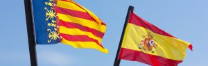 Banderas de la Comunitat Valenciana y España ondeando juntas bajo un cielo azul despejado