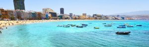 Playa de Las Canteras en Las Palmas de Gran Canaria con aguas turquesas, barcas y edificios al fondo