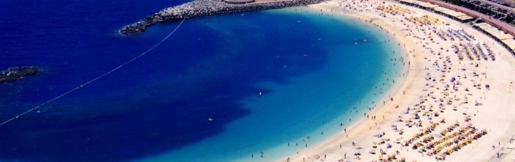 Vista aérea de la Playa de Mogán en Gran Canaria, con aguas turquesas en forma de herradura y arena dorada