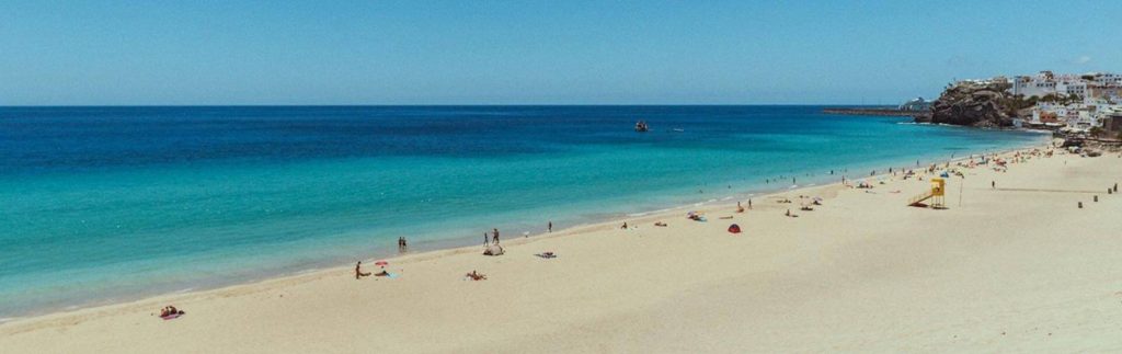 Playa del Matorral en Morro Jable, Fuerteventura, con arena blanca y aguas turquesas bajo cielo azul despejado