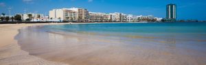 Playa del Reducto en Arrecife, Lanzarote, con aguas turquesas y el paseo marítimo al fondo en un día soleado